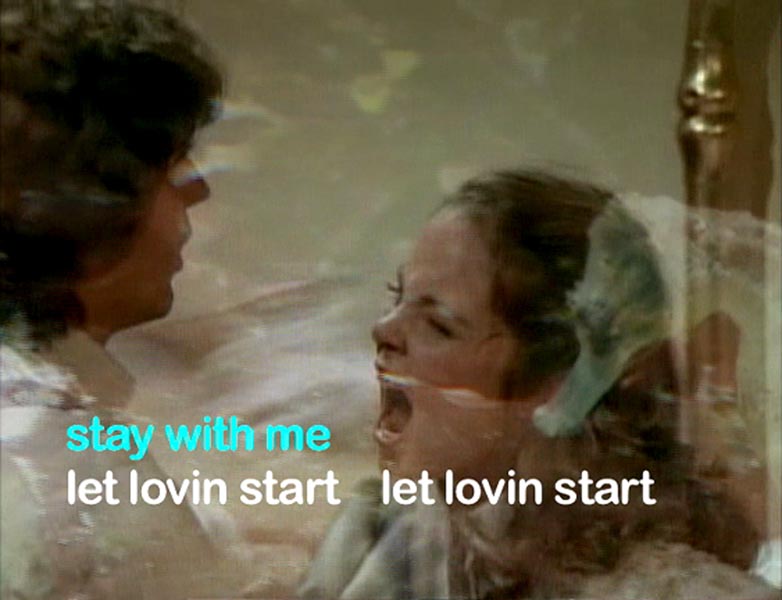 A man and a woman, facing each other. The woman is yelling, apparently in anger. There is overlaid text at the bottom. "Stay with me" in light blue, and "let lovin start" written twice in white.