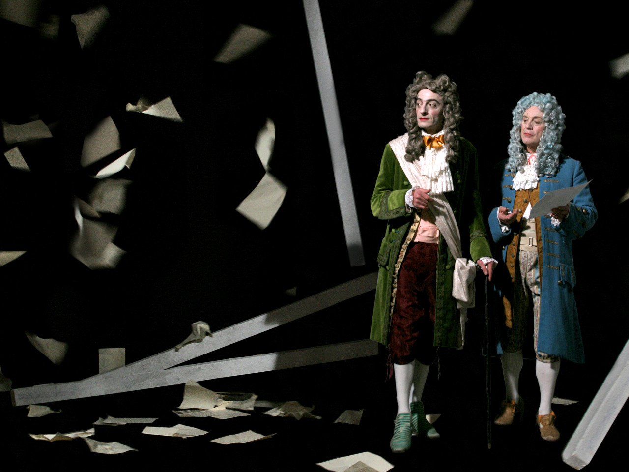 Two men in powdered wigs and colonial dress, surrounded by pieces of paper fluttering in the air and on the ground.
