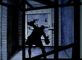 A animated cartoon in tones of black, blue, and grey depicting a silhouette of a prisoner with a chain on his leg and hands in the air, facing a large door with multiple locks.