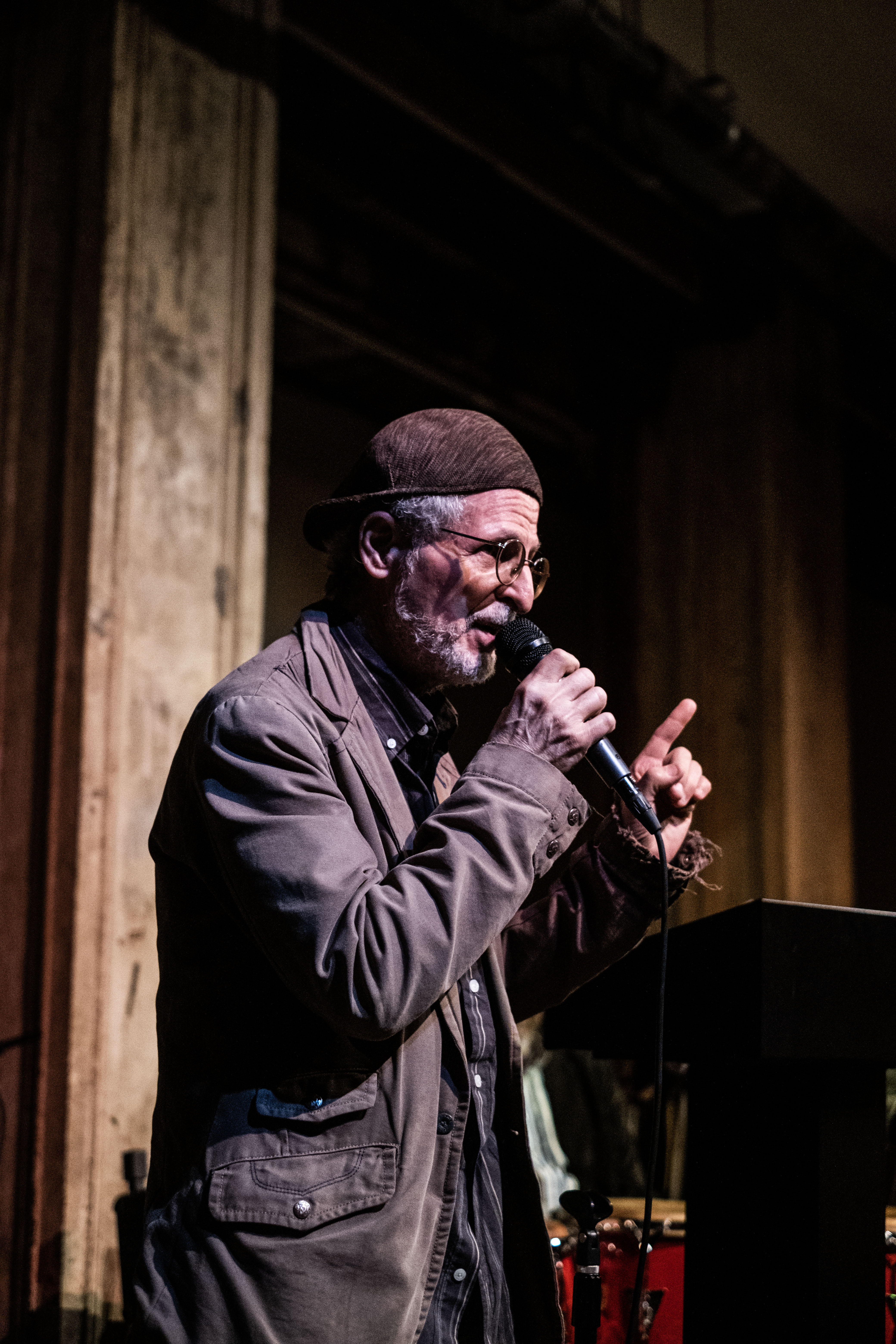 A figure stands on the stage with a mic, speaking to the crowd.