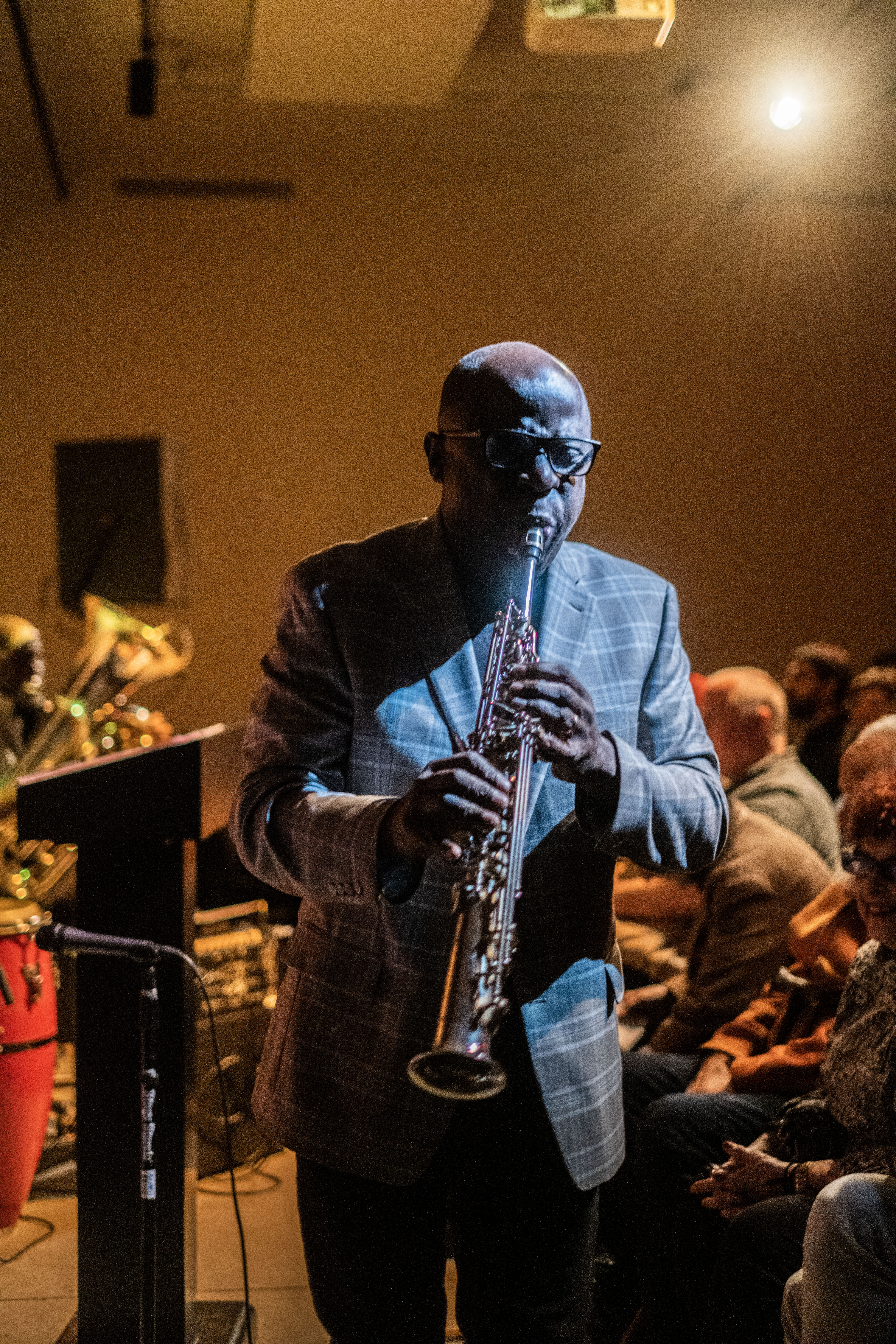 A figure plays the saxophone on a stage.