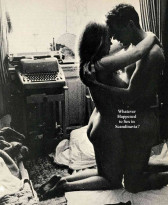 A grayscale image of two naked people, kneeling on the ground of an untidy room. They are embracing, with their foreheads pressed together. Behind them there is a window and a typewriter on a stand.