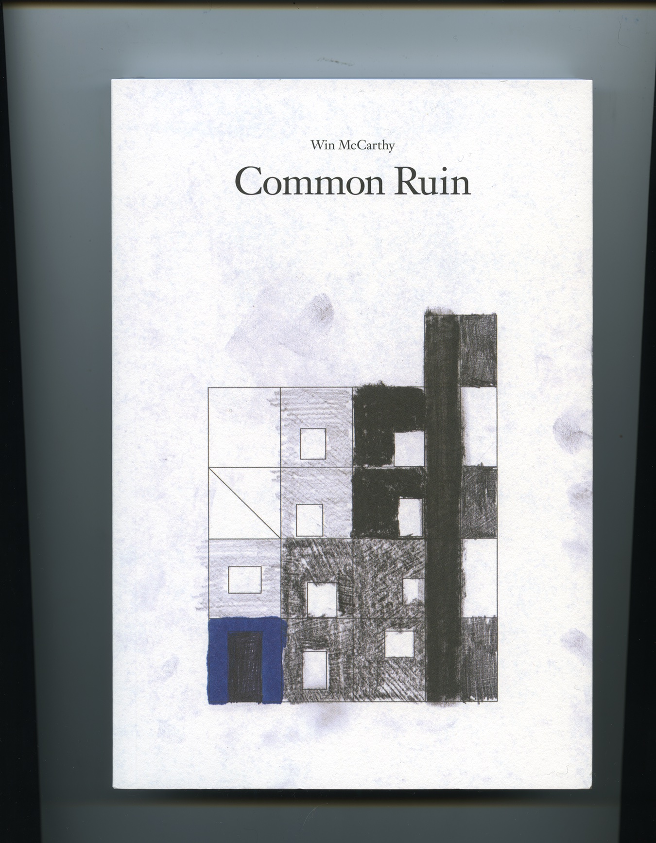 Scanned image of a white page featuring a geometric drawing of a building divided into squares. Some of the squares are colored in charcoal and others are lightly filled in with pencil. Light smudges of black charcoal appear across the page. In the upper-center of the page, text reads: 