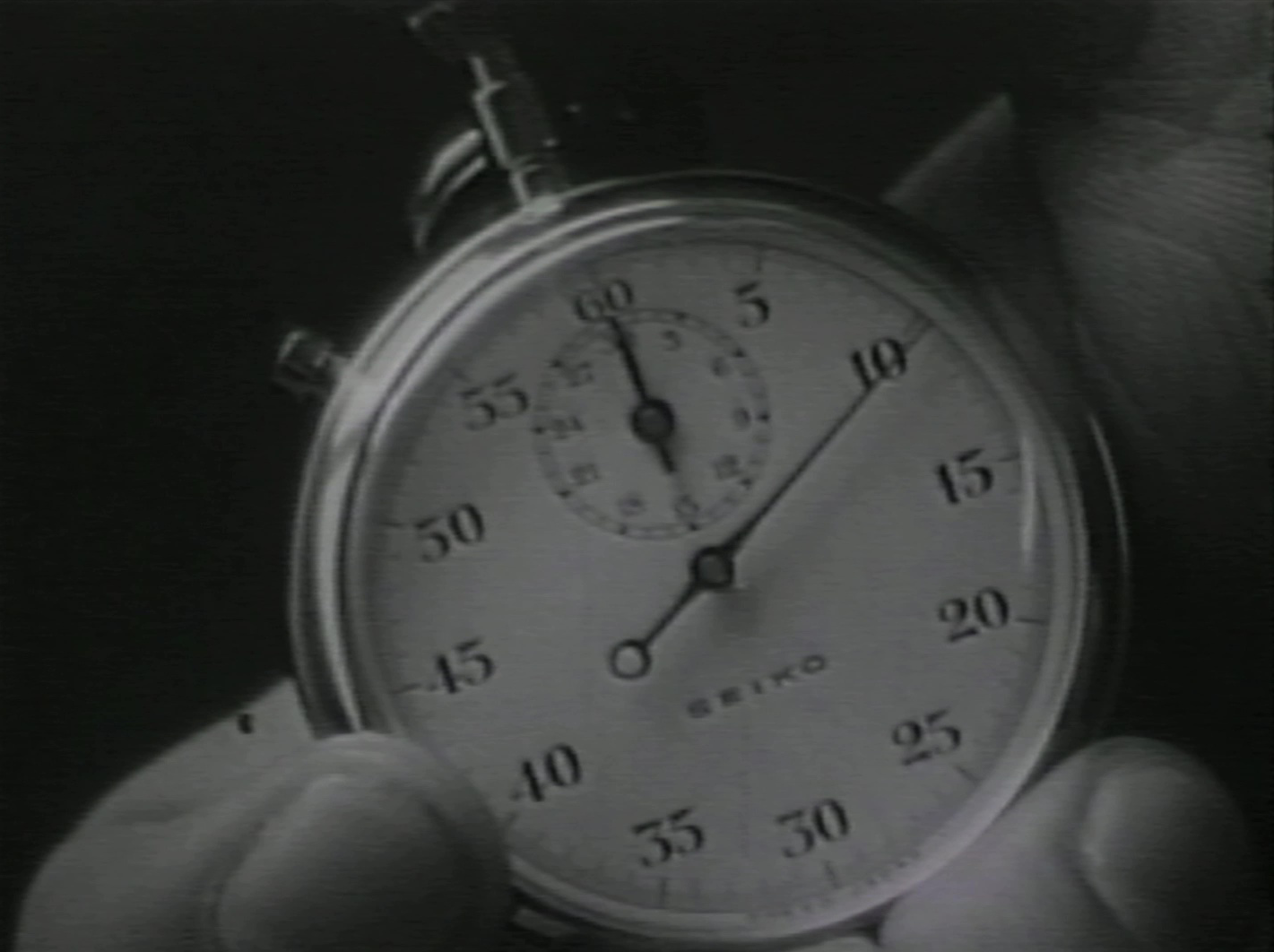 Black-and-white image of a hand holding a stopwatch.