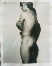 A black and white photo of a nude person in profile with arms crossed.