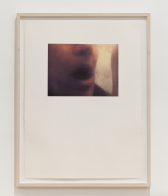 A photograph with a wood frame hangs on a wall. The photo sits on a white background, centered in the top half of the page. The photo shows a person's nose and mouth, with mouth agape.