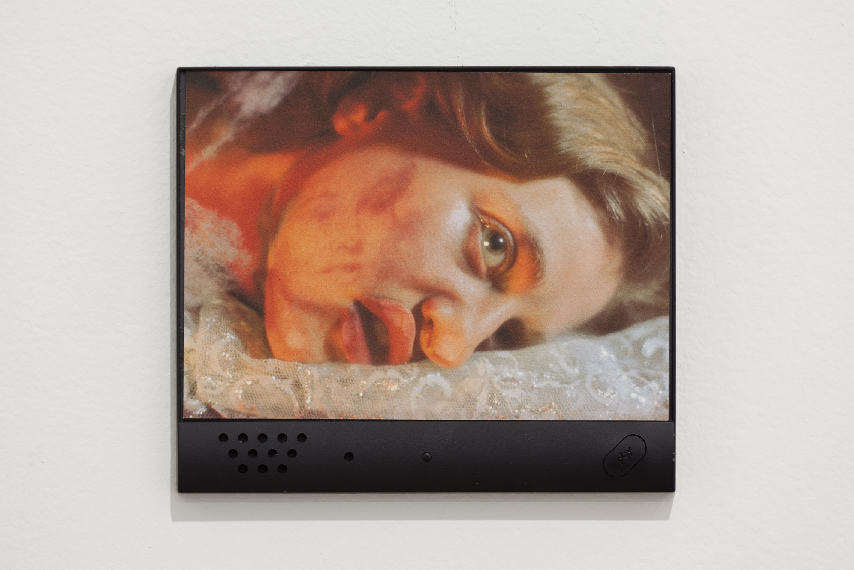 The image shows a photograph with a plastic frame. The frame has holes for a small speaker and a button that says, 