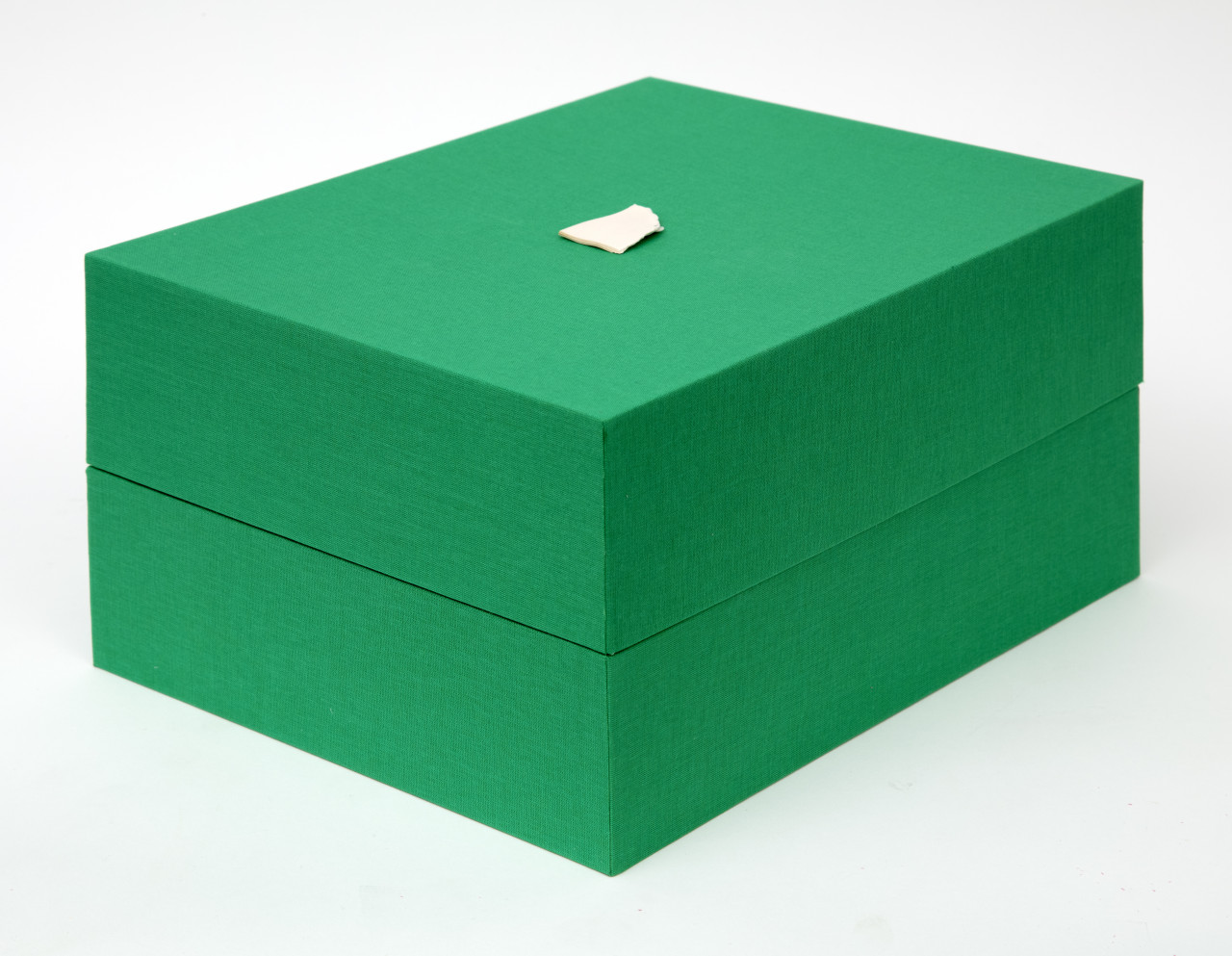 A green rectangular box against a white background. The lid and base of the box meet in the center, and a small bit of torn paper is glued on top.