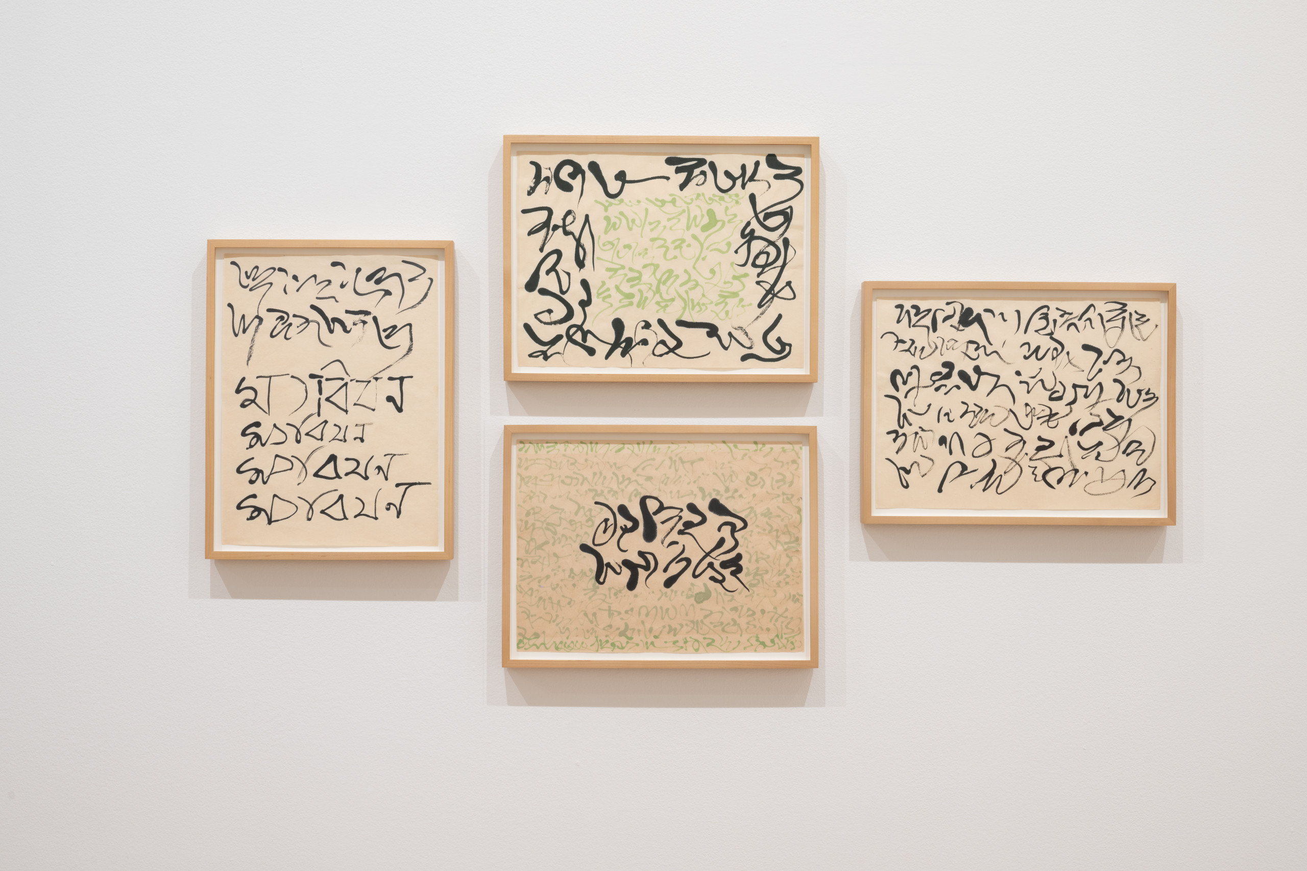 A cluster of four works on paper against a white gallery wall. The works feature swooping, abstract calligraphic strokes in black and light green ink.