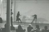 A black and white image of a performance by two individuals tugging on opposite ends of fabric.