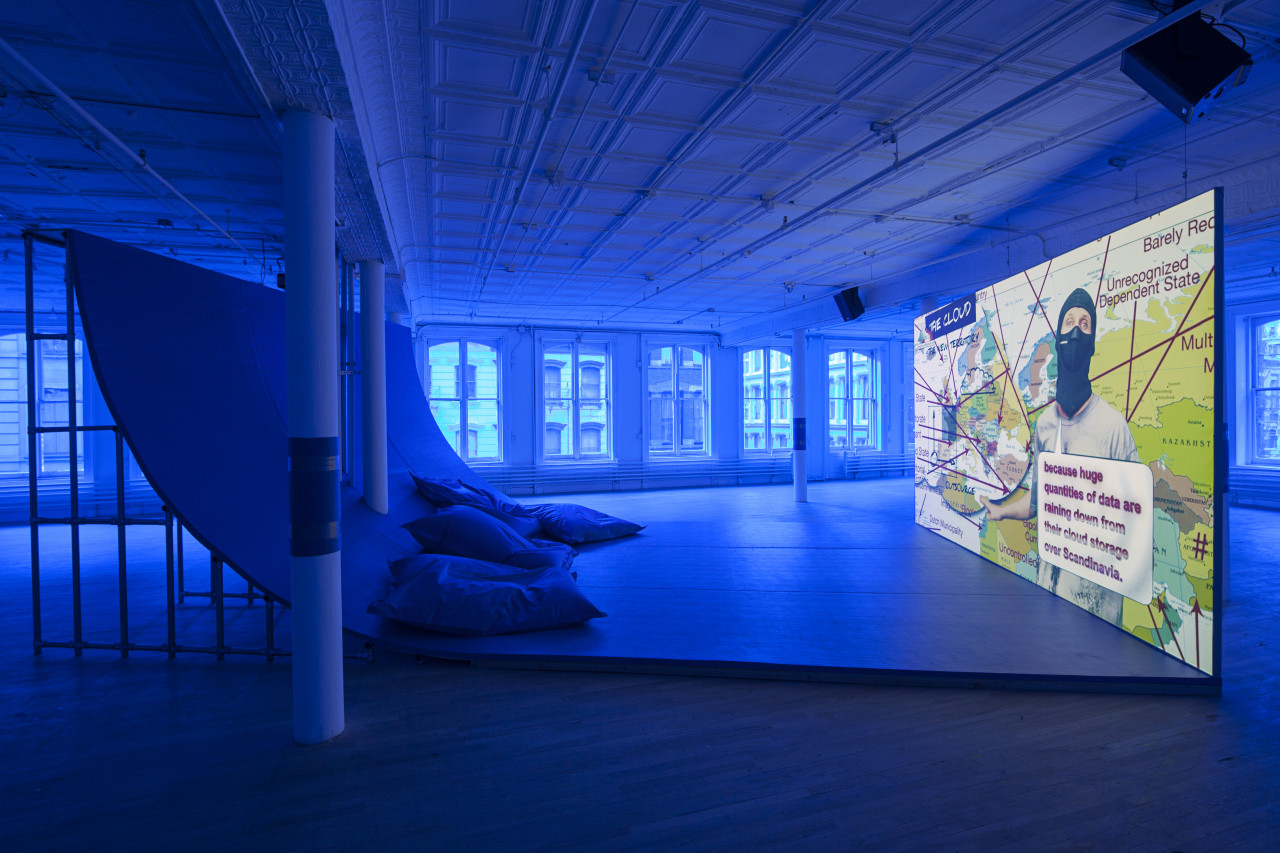 A video projection playing in a blue lit room with a large curved surface for viewing.