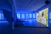 A video projection playing in a blue lit room with a large curved surface for viewing.