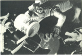 A black and white image of a toy alligator holding a medicine bottle, surrounded by miscellaneous objects.
