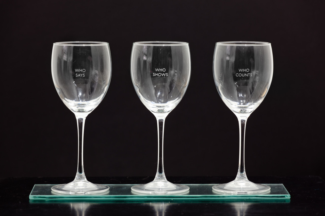 Three empty wine glasses in  row, each engraved with two words: 