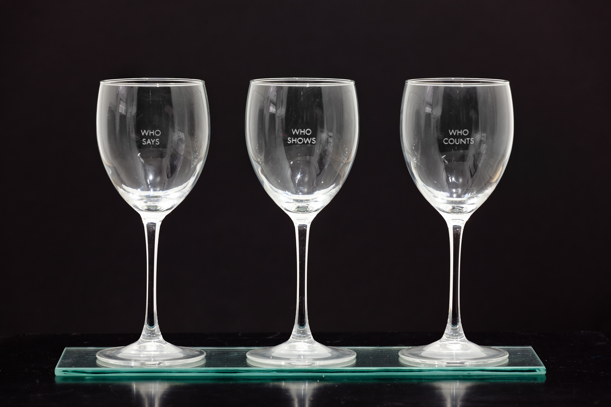 Three empty wine glasses in  row, each engraved with two words: 