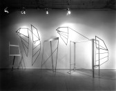 A black and white image of multiple sculptures along a wall.