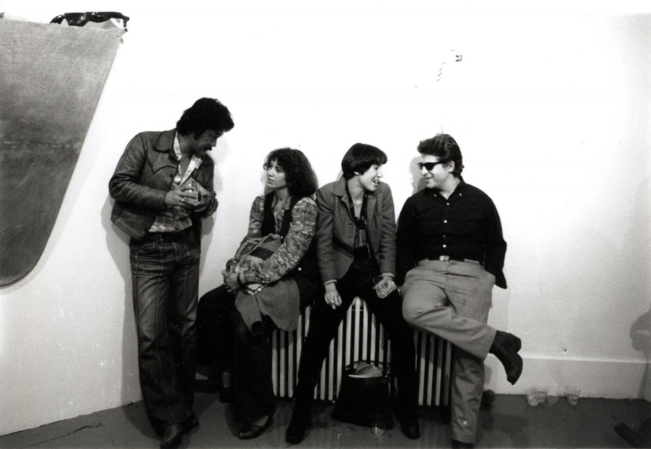 A group of individuals in conversation while sitting on a radiator.