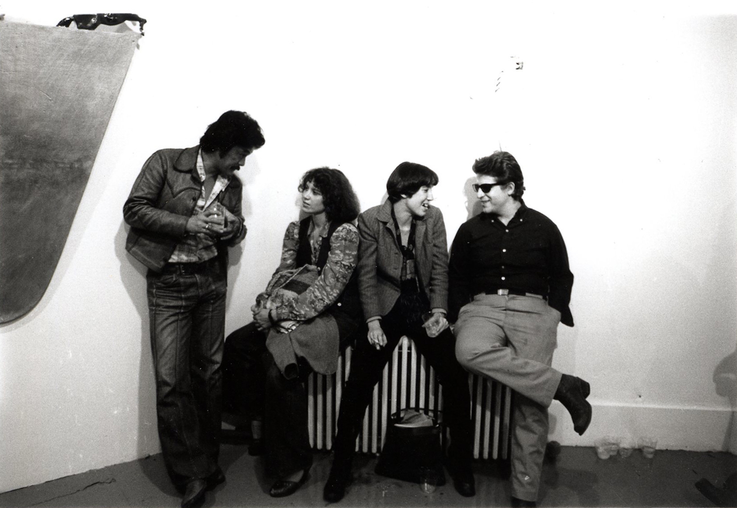 A group of individuals in conversation while sitting on a radiator.