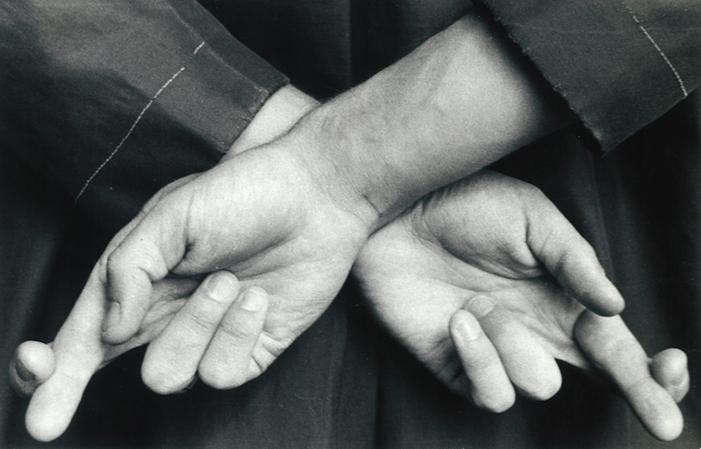 An close up black and white image of an individual with their fingers crossed behind their back.